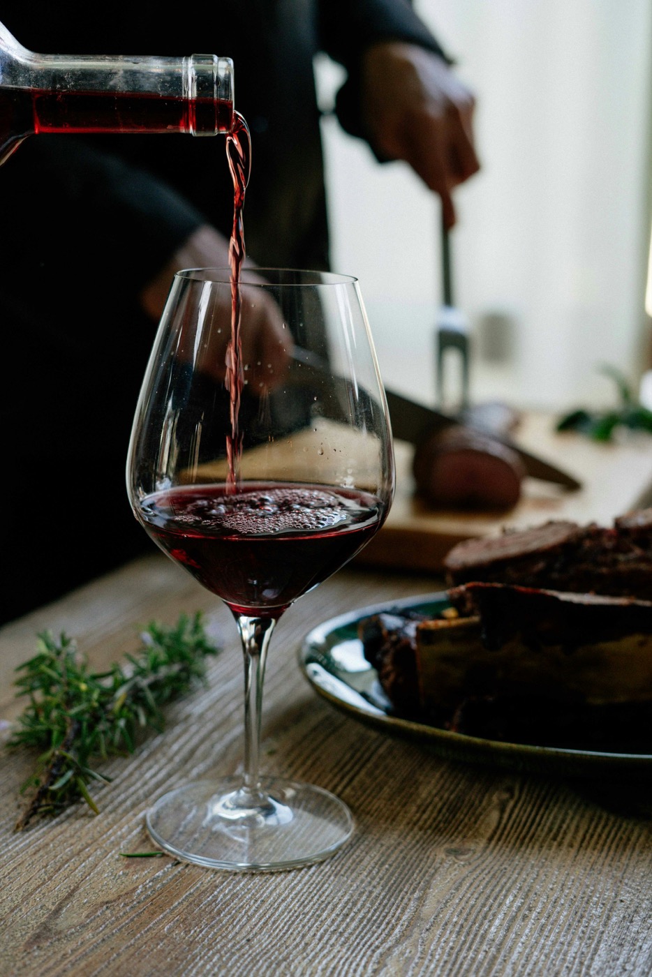 Rotwein wird am Tisch eingeschenkt
