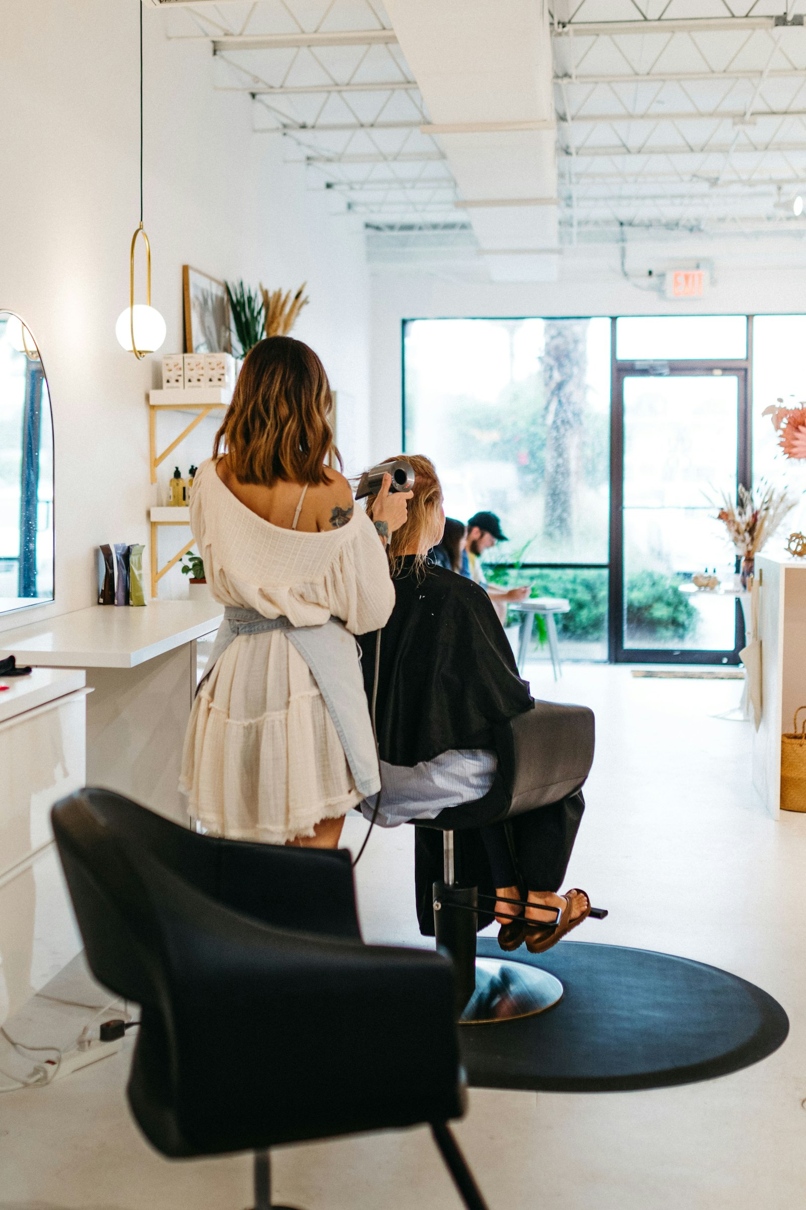 Stylistin föhnt einer Kundin die Haare im hellen Studio Nine Salon